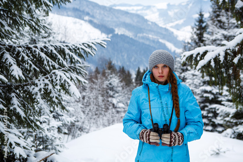 Portrait of girl with binoculars in hand on the background of winter mountains