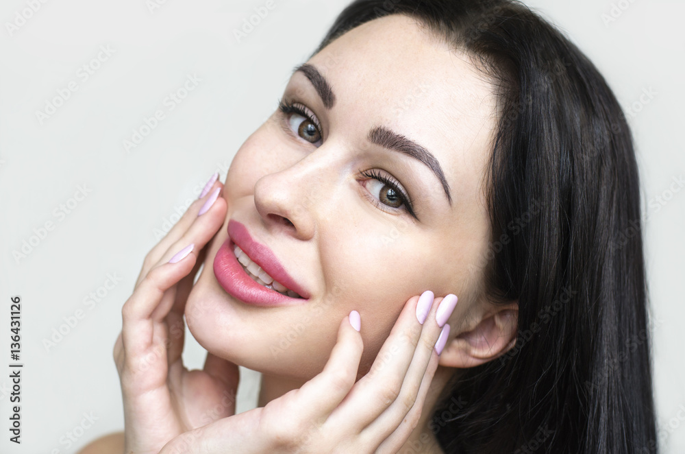 Pretty girl with big eyes and dark eyebrows, looking at camera and smiling, a model with light nude make-up, gray studio background Pretty girl with big eyes and dark eyebrows, looking at camera and smiling, a model with light nude make-up, gray studio background