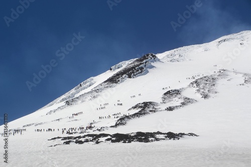 The packed Villarrica volcano in Chile, lines of people following the boot pack up the mountain. 