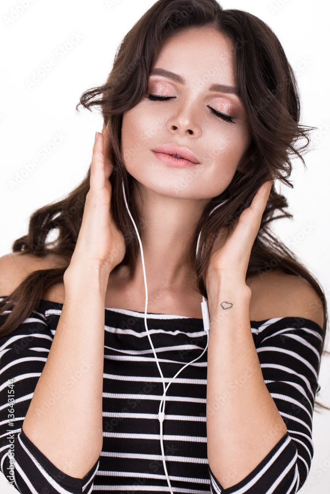 Beautiful woman with healthy skin, hair curls and headphones, posing in studio. Beauty face Beautiful woman with healthy skin, hair curls and headphones, posing in studio. Beauty face