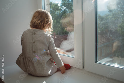 Little girl sits on a windowsill