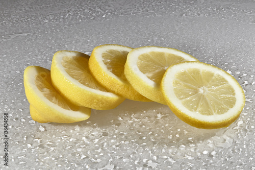 Zitrone aufgeschnitten auf weisser Glasplatte mit Wassertropfen