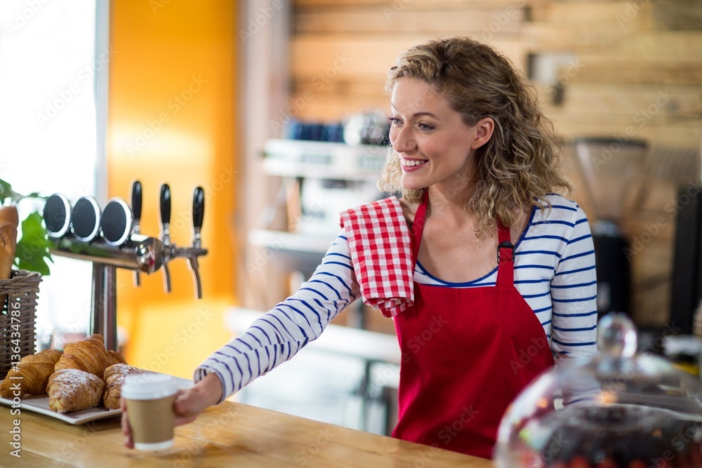 Waitress serving a cup of coffee to customer in café