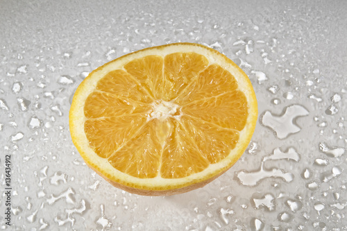 Orange aufgeschnitten auf weisser Glasplatte mit Wassertropfen