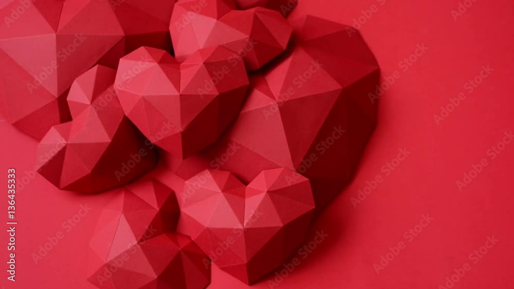 Heap of red polygonal paper heart shapes on red background, top view, rotating video Heap of red polygonal paper heart shapes on red background, top view, rotating video