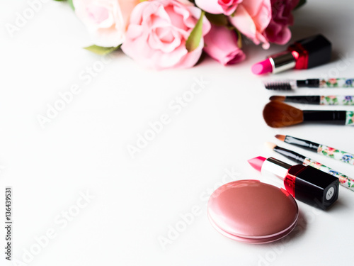 Make up products lipstick, blush and tools brushes with pink roses flowers on white background. Lifestyle woman still life