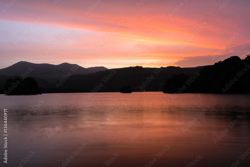 Coucher de soleil en Auvergne autour du Lac Chambon. Nuages et reflets oranges, roses