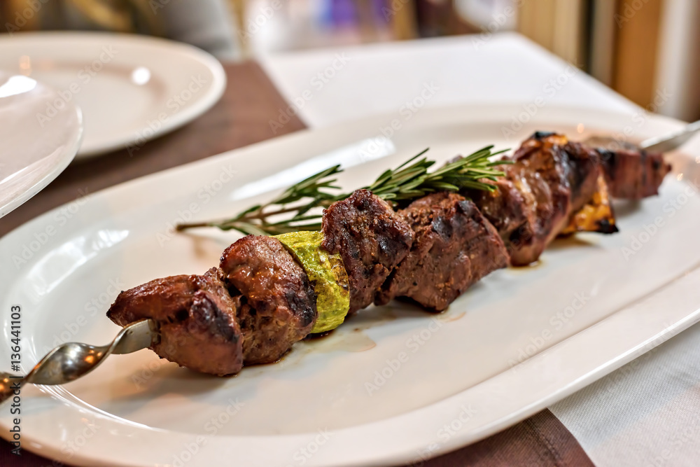 Beef kebab with vegetables and rosemary seasoning on a white plate Beef kebab with vegetables and rosemary seasoning on a white plate