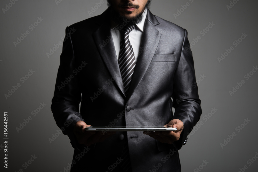 Handsome Businessman Looking at a tablet, isolated in black. Handsome Businessman Looking at a tablet, isolated in black.