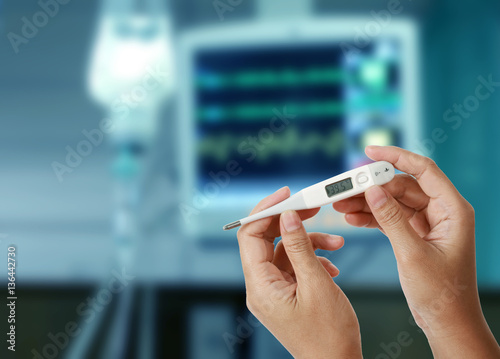 Thermometer showing high temperature in hands with drop of salin photo