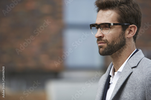 Thinking man in glasses and coat