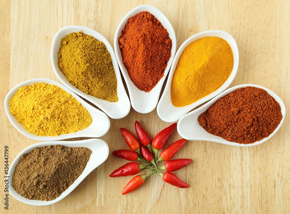 Aromatic and colorful spices in ceramic containers on a wooden background. Aromatic and colorful spices in ceramic containers on a wooden background.