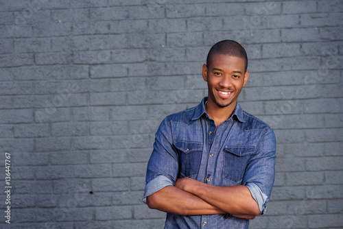 African man smiling against gray wall with blue shirt