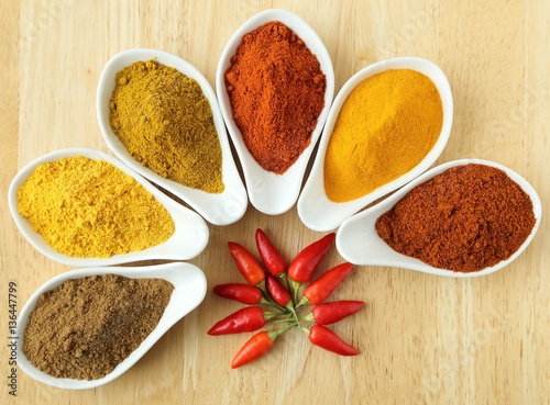 Aromatic and colorful spices in ceramic containers on a wooden background.