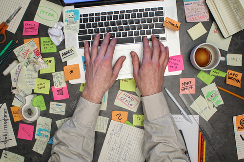 Top view on man working on laptop computer with post it notes all