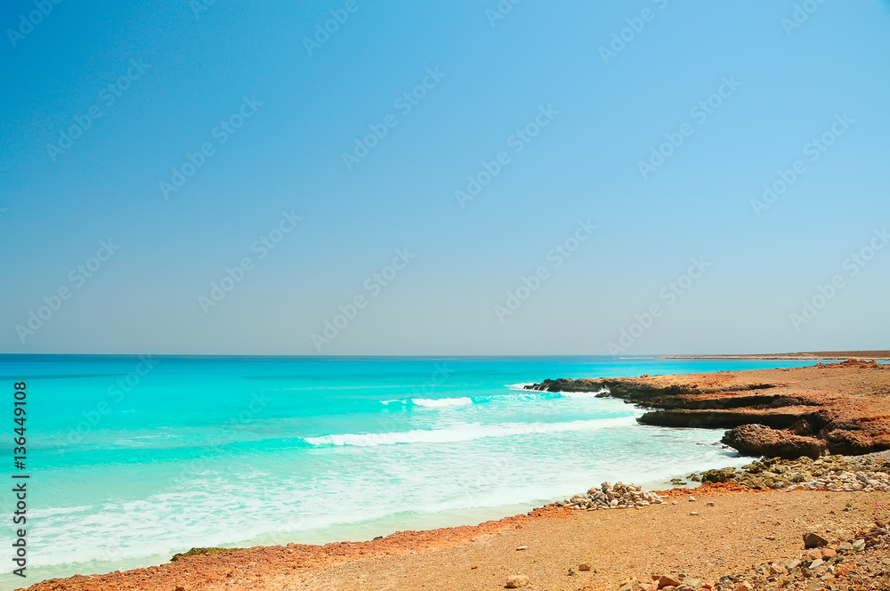 sandy desert lifeless rocky shore coastline of the  sea. Mountain skolny, cliffs descend to the water on the horizon. Socotra, Yemen. Turquoise amazing color clean water into the sea. 
