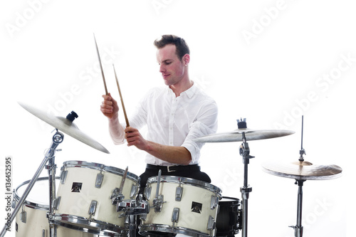 drummer behind drum set wears white shirt and plays the drums photo