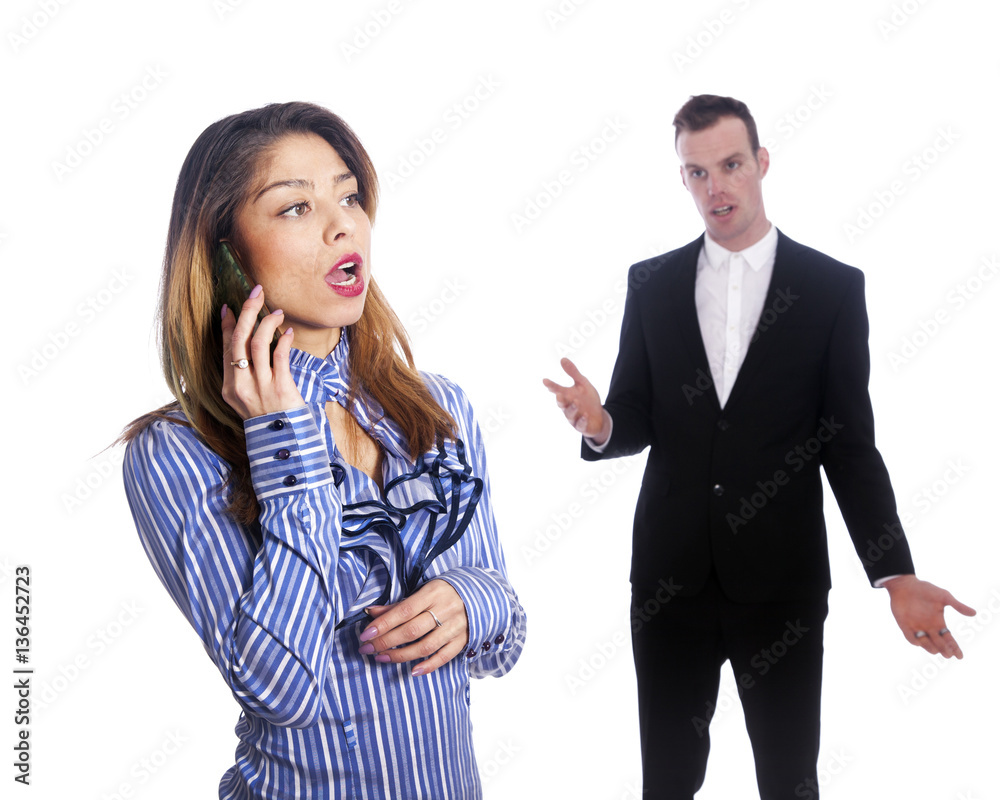 young woman talks into mobile phone while boss looks from behind young woman talks into mobile phone while boss looks from behind