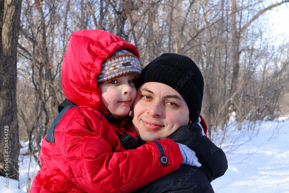 Happy father and little son in winter snow forest