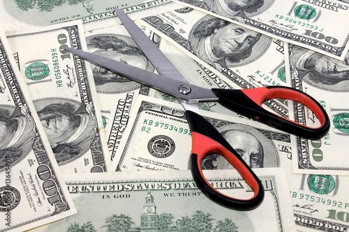 Concept of spending money - scissors cut money on background