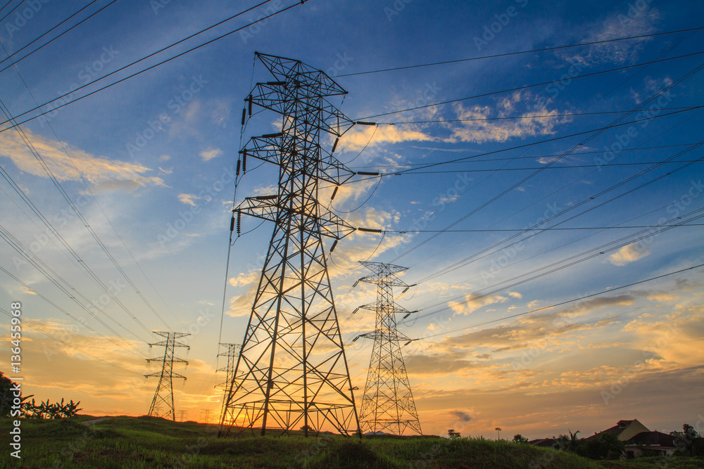 Fototapeta premium A high voltage of transmission tower in the morning sunrise with the beauty of a blue sky