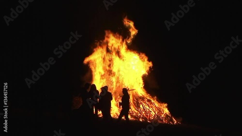 Silhouettenhaft sieht man Leute rund ums nächtliche Osterfeuer stehen