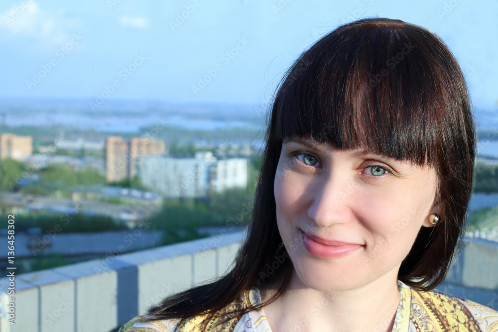 Close-up portrait of young beautiful black hair smiling woman on city background, sunny day