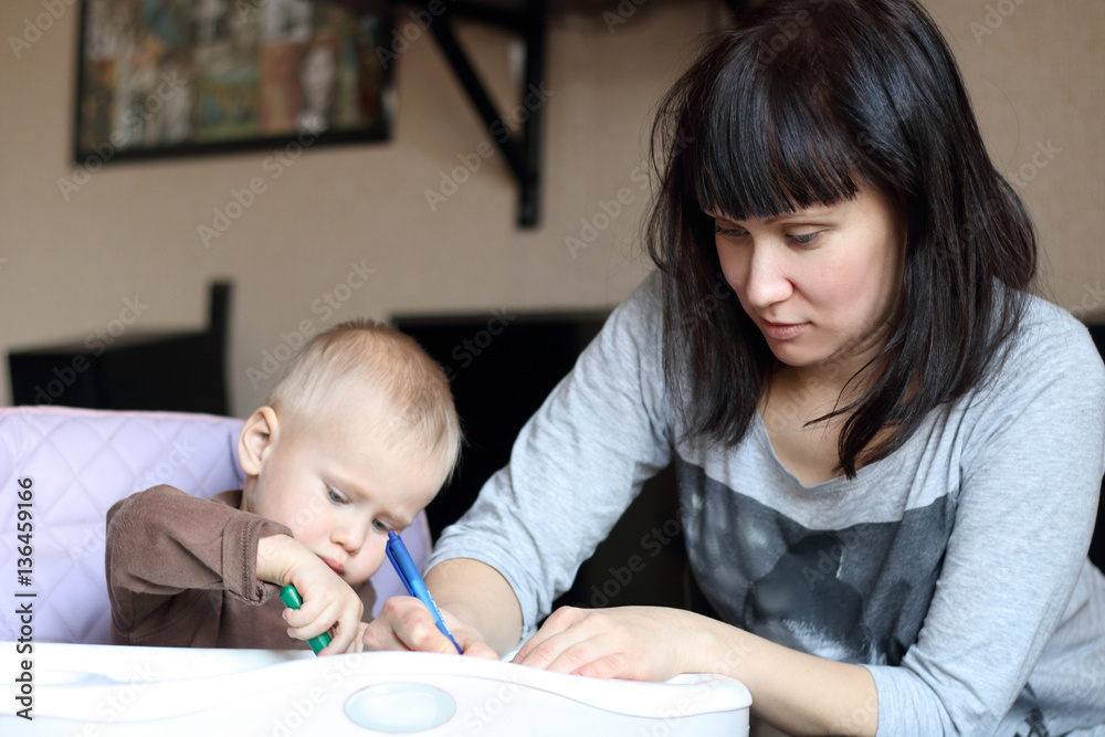 Young mother with little son drawing together by pencils on pape Young mother with little son drawing together by pencils on pape