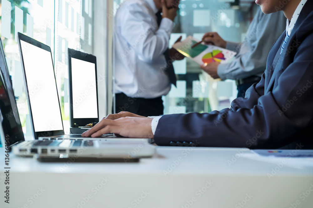 business man using laptop computer on office table with two partners interacting on background business man using laptop computer on office table with two partners interacting on background