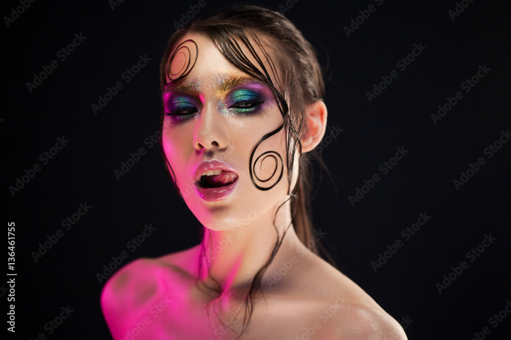 Young beautiful girl bright makeup with a wet look shine, dark background Young beautiful girl bright makeup with a wet look shine, dark background