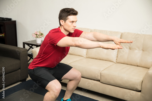 Athletic young man exercising at home