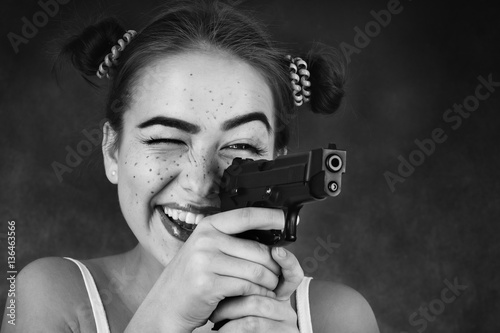 fun teenager girl with gun on black background, monochrome