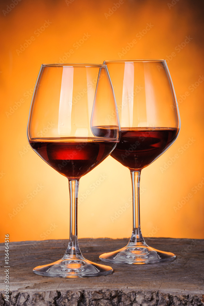 Two glasses of red wine close-up over golden background.