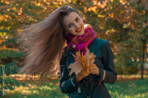 beautiful girl with long hair who fly on the wind keeps the leaves in their hands and smiles