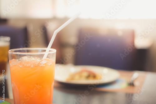 Orange juice with blur breakfast in restaurant background.