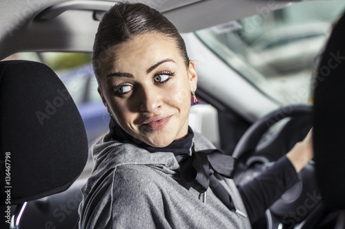 Beautiful woman backing up her car from the parking lot. Smiling young woman driving her car. © Addoro