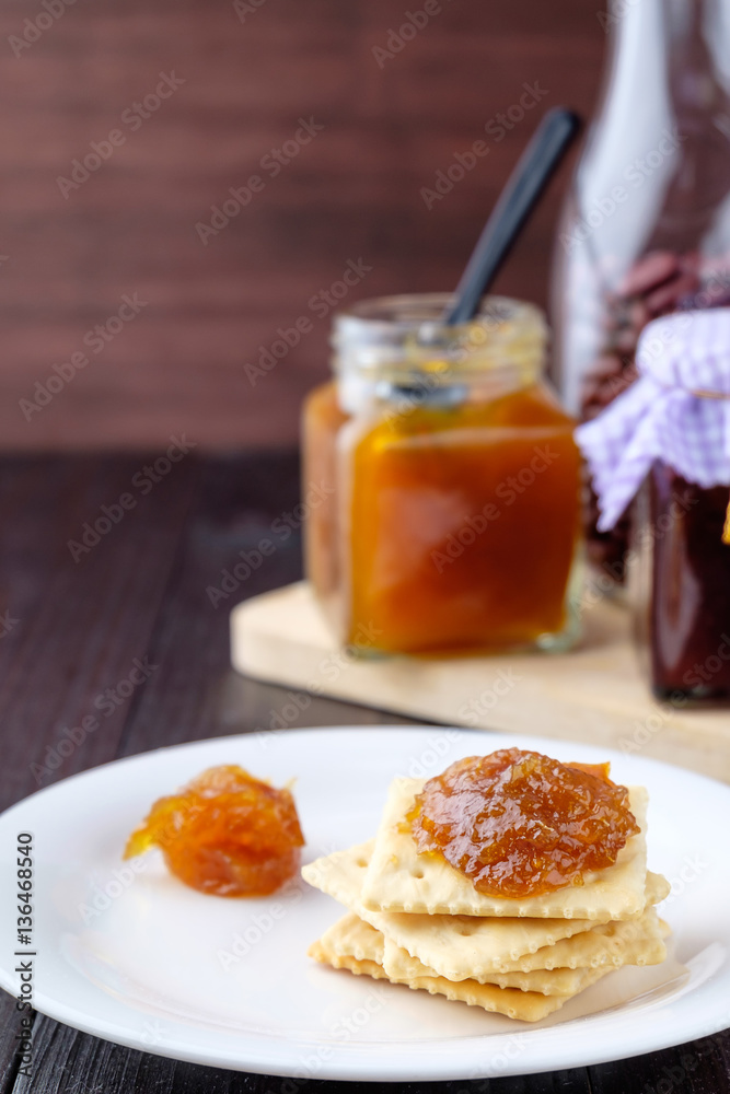 Crackers with orange jam on wooden background