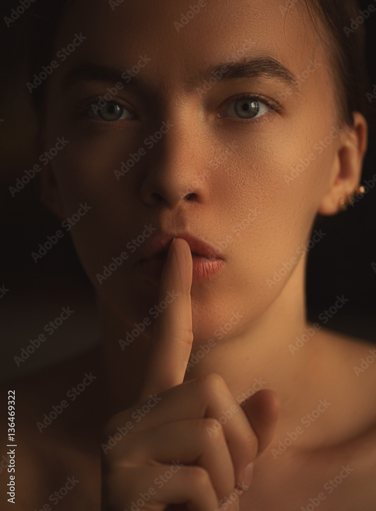 Fototapeta premium young beautiful girl holding a finger to her mouth