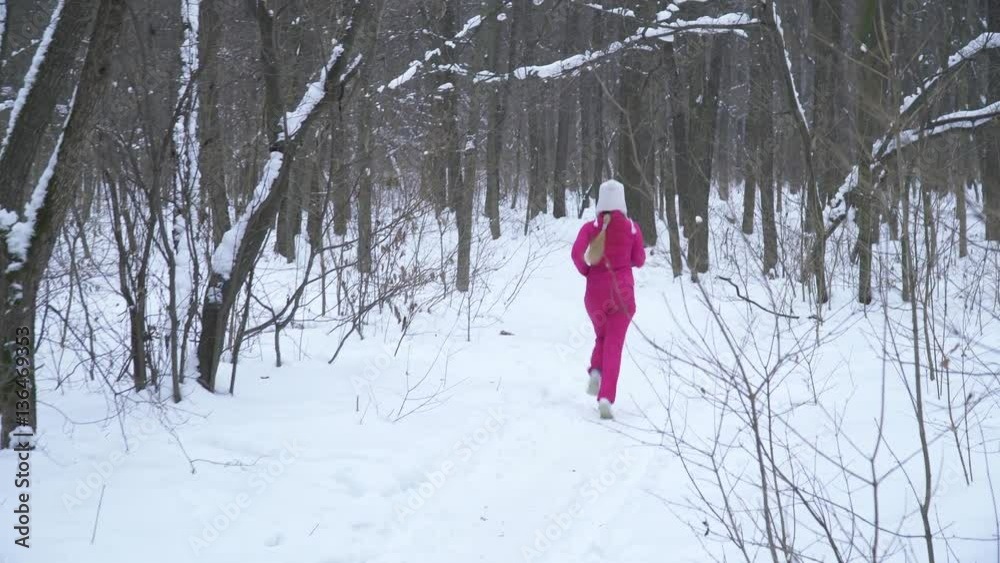 Back view of young blonde woman running in winter forest Back view of young blonde woman running in winter forest