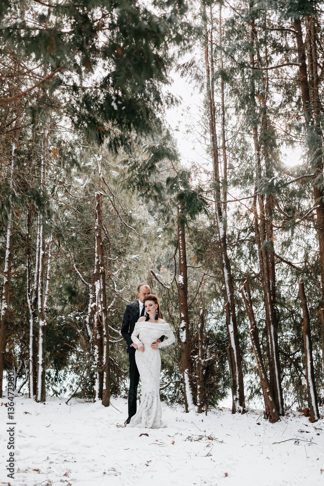 Stylish groom with the bride in the forest in winter