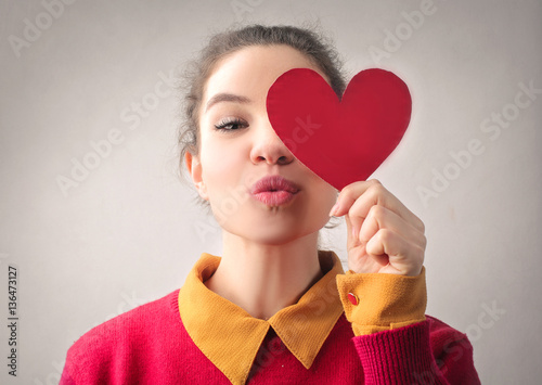 Girl giving kiss and holding heart photo