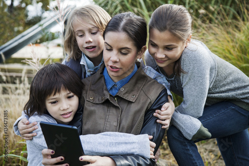 Teacher showing tablet computer to school children during field trip photo