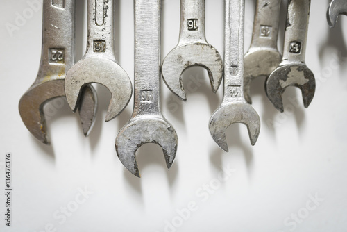 Close-up of wrenches hanging on white wall at workshop photo