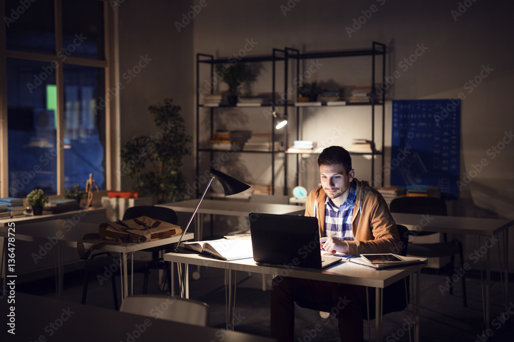 Confident student studying in library at night Confident student studying in library at night