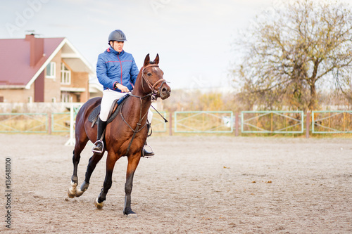 Young sportsman riding horse on equestrian training.