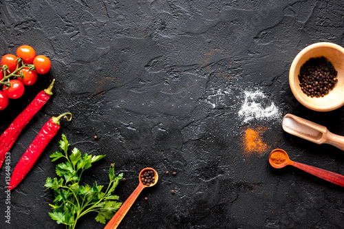 spices in wooden spoon on dark background top view