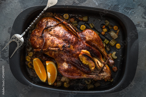 Roast duck with oranges and apples in a frying pan, dark photo, top view
