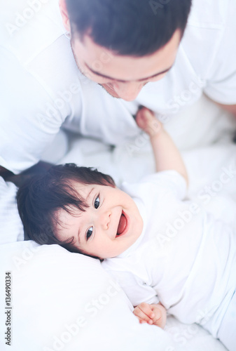 Baby boy lying on bed, next to his father