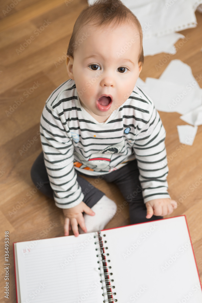 Ten months old baby girl playing with papers and paper folder on