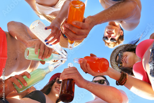 Happy friends having fun with cocktails on beach, bottom view